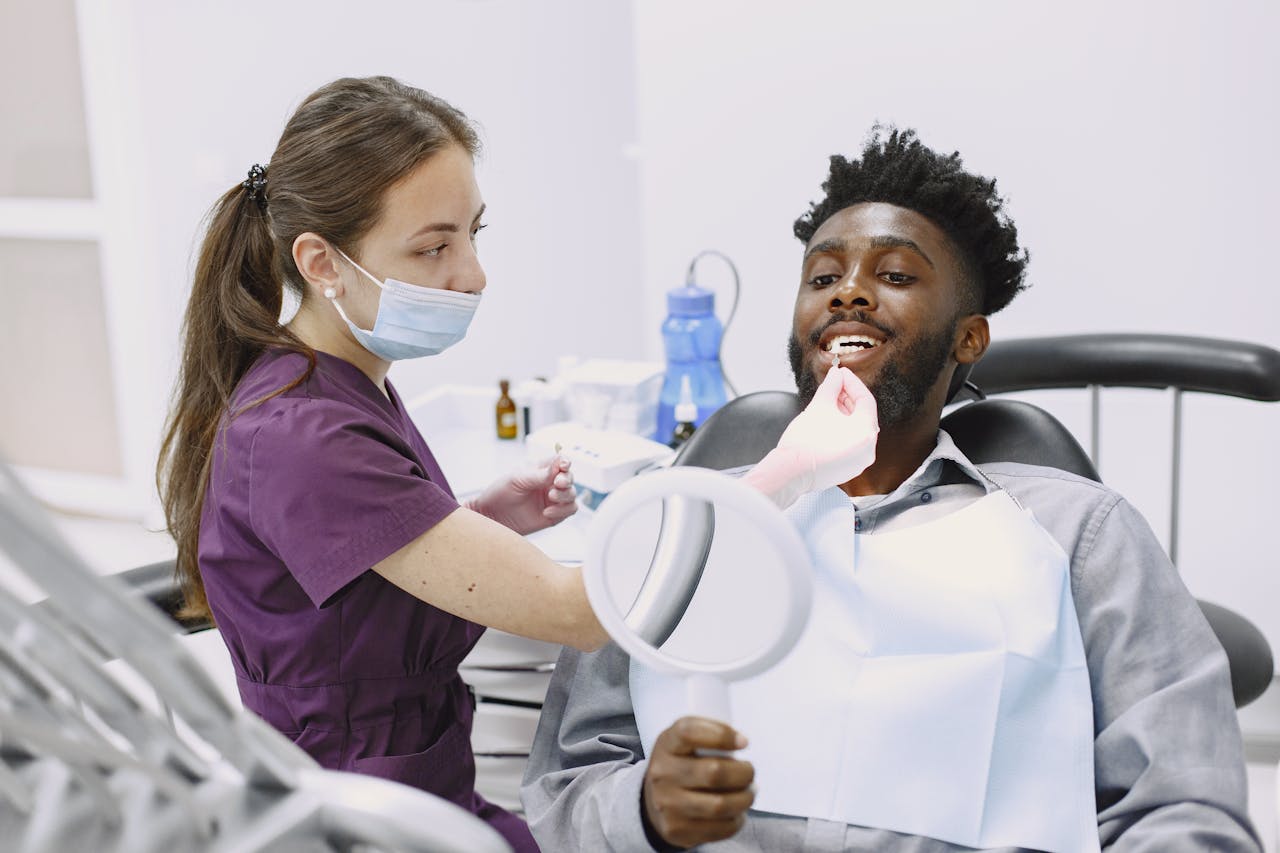 A dentist performs a check-up on a patient holding a mirror in a modern dental office.